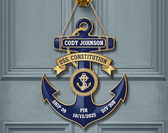 May include: A navy blue anchor-shaped wooden door hanger with gold accents and rope. The door hanger features the name "CODY JOHNSON" and "USS. CONSTITUTION" in gold lettering. Additional text includes "SHIP 09", "PIR 10/15/2025", and "DIV 308".
