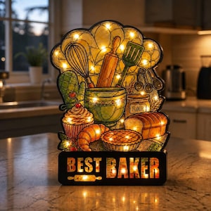 May include: A decorative light-up sign featuring a stained-glass style illustration of baking tools including a whisk, rolling pin, spatula, and measuring spoons, alongside a cupcake, croissant, pie, and bread, with the text BEST BAKER at the base.