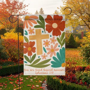 May include: A garden flag featuring a floral design with a wooden cross at the center. The flag has orange, teal, and pink flowers with green leaves. The text "You are loved beyond measure Ephesians 3:19" is printed at the bottom.