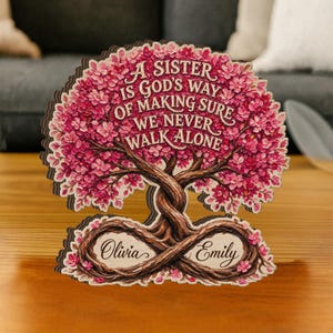 May include: Wooden tree-shaped decorative piece with pink blossoms and the text "A SISTER IS GOD'S WAY OF MAKING SURE WE NEVER WALK ALONE." Features the names "Olivia" and "Emily."