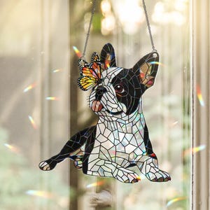 Peut inclure: Un attrape-soleil en vitrail en forme de bouledogue fran&ccedil;ais avec des segments noirs et blancs. Un papillon monarque aux ailes orange, noires et blanches repose sur une oreille. L'objet est suspendu par une cha&icirc;ne argent&eacute;e et inclut du verre iris&eacute;.