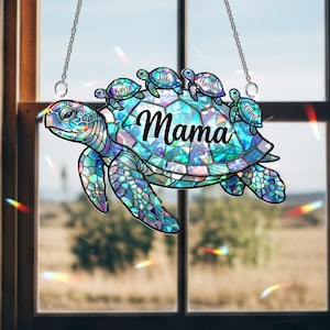 May include: A stained-glass style sea turtle suncatcher with the word "Mama" and the names Kayla, Josi, Hannah, and Liam. The turtle is primarily blue and turquoise, with a chain for hanging.