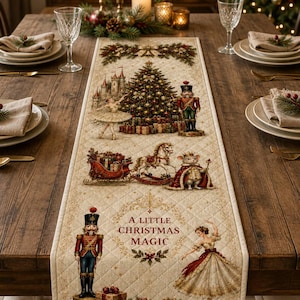 May include: A quilted cream-colored table runner featuring a festive Christmas scene with a nutcracker, a ballerina, a rocking horse, a mouse king, and a decorated tree. The text A LITTLE CHRISTMAS MAGIC is printed in the center in red lettering.