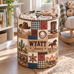 Pode incluir: Um cesto de armazenamento cilíndrico de tecido com um design de patchwork acolchoado e ilustrações de temática western, incluindo um chapéu de cowboy, botas, um laço, um cacto, um cavalo e uma fogueira. O nome Wyatt James está no centro.