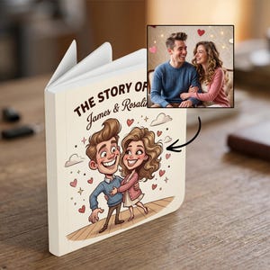 May include: A custom book with a cream-colored cover featuring a cartoon illustration of a couple and the text 'THE STORY OF James & Rosalind'. An inset photo shows a real couple, with a black arrow pointing from the photo to the illustration.