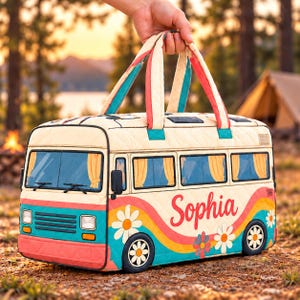 May include: A quilted fabric bag shaped like a camper van with a cream base, teal and coral accents, and yellow daisy graphics. The side features the name Sophia in red script. It has two top handles and windows with yellow curtains.