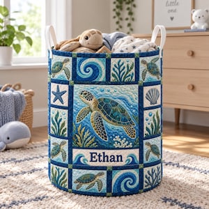 May include: A cylindrical fabric storage basket featuring a quilted pattern with sea turtles, starfish, seashells, and ocean waves in shades of blue and green. The center panel displays the name Ethan in dark blue text with white trim.