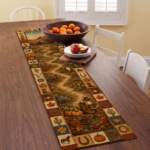 May include: A rectangular table runner featuring a western-themed landscape with a winding path, cacti, pumpkins, horses, and lanterns. The border consists of square panels displaying horseshoes, boots, leaves, and stars in warm autumn tones.
