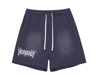 May include: Navy blue shorts with a white drawstring and pockets. The shorts feature the word "HEAVENLY" in a white, gothic-style font across the front. The shorts are made of a soft material.