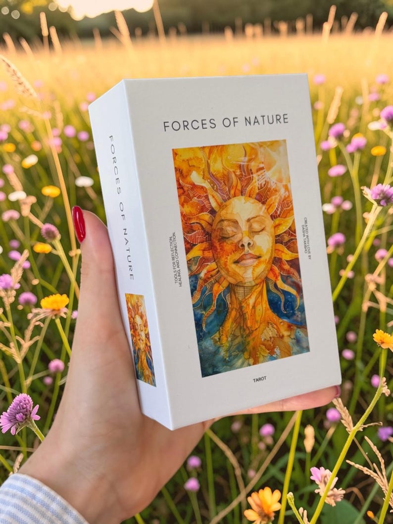 May include: A white rectangular tarot deck box titled Forces of Nature. The front features a vibrant watercolour illustration of a sun-faced figure with orange and yellow rays. Text includes Forces of Nature, Tools for Reflection, Healing and Connection, and Tarot.