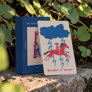 May include: A deck of tarot cards in a dark blue box with the text THE HIDDEN and TAROT. A single card titled Knight of Winds shows a person riding a red horse under a blue cloud with blue lightning bolts, all set against a light beige background.