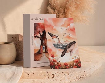 May include: A deck of Metaphorical Associative Cards in a white box. The card in front features a surreal illustration of a whale with a seascape on its back, a lighthouse, birds, and red poppies under a soft pink and orange sky.