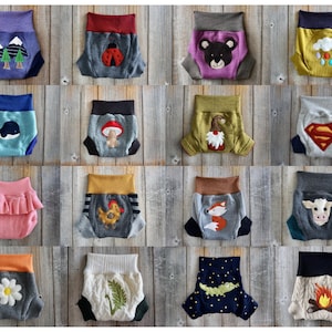 Może przedstawiać: Kolekcja 16 kolorowych, wzorzystych i haftowanych pieluch materiałowych dla niemowląt. Każda pielucha ma inny wz&oacute;r, w tym zwierzęta, sceny z natury i wzory geometryczne.