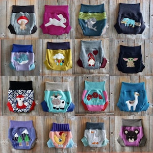 Może przedstawiać: Kolekcja 16 kolorowych, wielokrotnego użytku pieluch materiałowych z r&oacute;żnymi wzorami inspirowanymi zwierzętami i naturą. Każda pielucha ma inny haftowany wz&oacute;r, w tym kr&oacute;lika, rekina, gnoma, lamy, krowę, lisa, kurczaka, gęś, niedźwiedzia, wieloryba, grzyba, chmurę, g&oacute;rę, drzewo, kwiat i postać przypominającą Yodę.