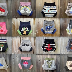 Może przedstawiać: Kolekcja 16 kolorowych, wzorzystych i ozdobionych aplikacjami pieluch materiałowych. Każda pielucha ma inny wz&oacute;r, w tym grzyb, tęczę, wieloryba, żagl&oacute;wkę, wiśnię, drzewo, słonia, cytrynę, lisa, kotwicę, dinozaura, babeczkę, sowę i małpę.