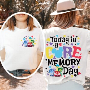 May include: White t-shirt featuring characters from the animated movie "Inside Out." The front of the shirt has a small graphic of the characters. The back of the shirt has the text "Today is a CORE MEMORY Day" in colorful letters.