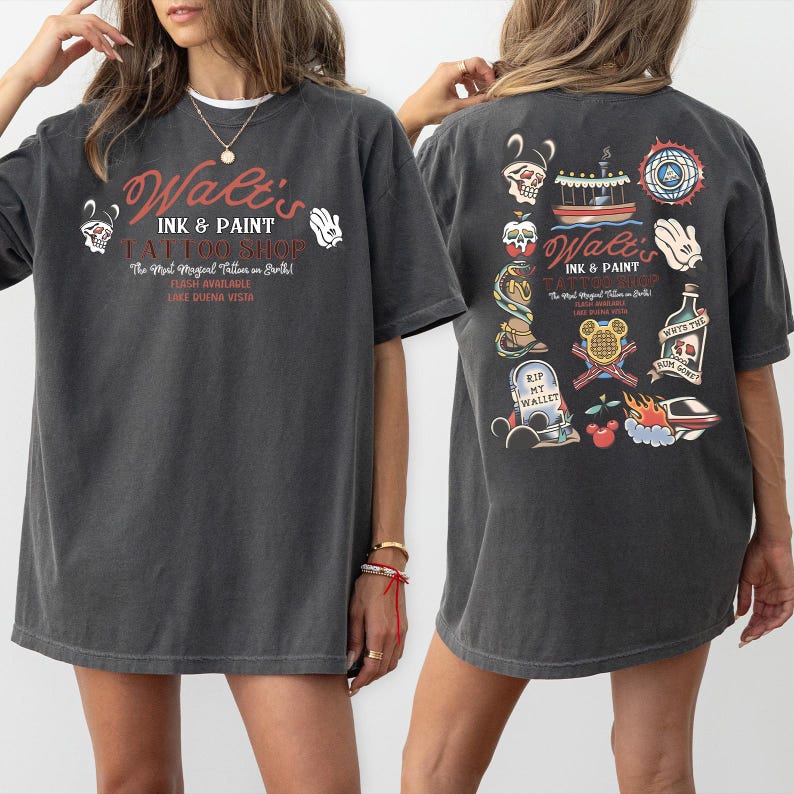 May include: Dark gray t-shirt with the text "Walt's Ink & Paint Tattoo Shop" in red and white. The front of the shirt features the shop's name and logo. The back has various tattoo-style illustrations, including a skull, a boat, and a Mickey Mouse hand.