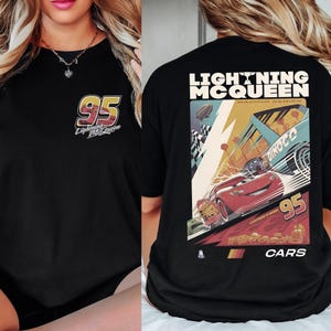 May include: Black t-shirt featuring Lightning McQueen from the Cars movie. The front has a small logo with the number 95. The back displays a large graphic of Lightning McQueen racing, with the text "LIGHTNING MCQUEEN RACING SERIES" and "CARS".
