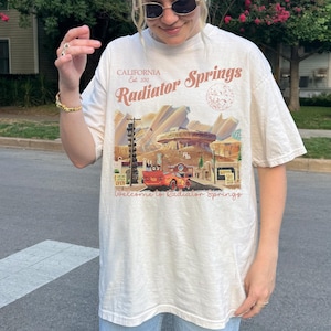 May include: A white ceramic mug with a black handle and the text "But First, Coffee" in a black, bold font. The mug is on a white surface.