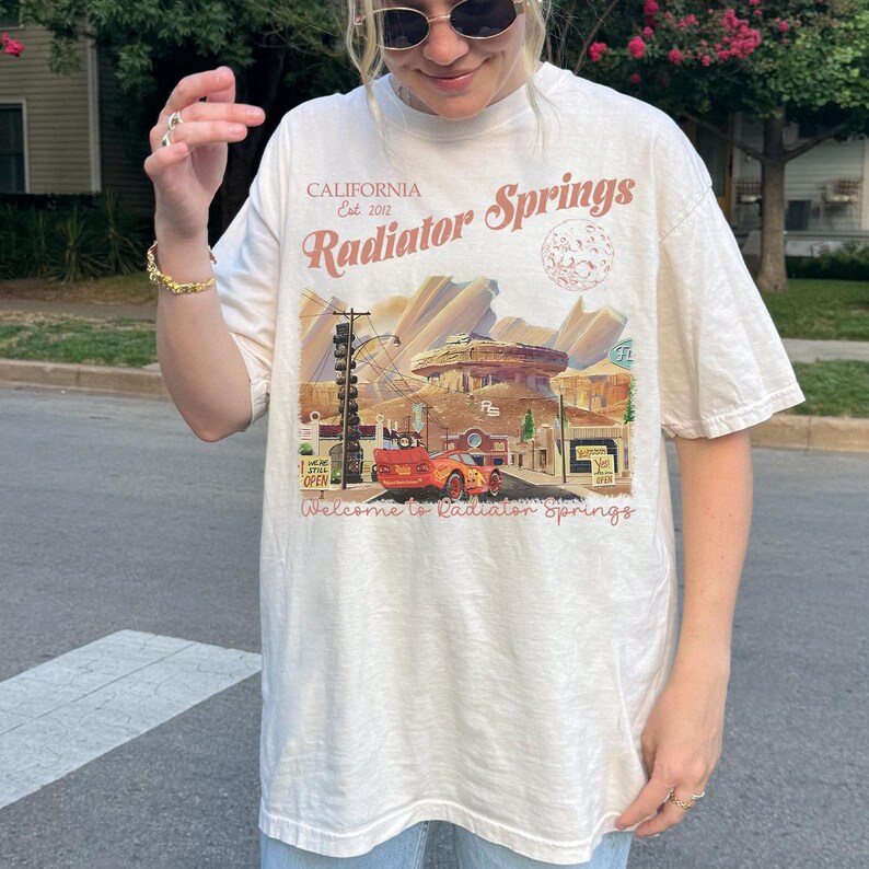 May include: A white ceramic mug with a black handle and the text "But First, Coffee" in a black, bold font. The mug is on a white surface.