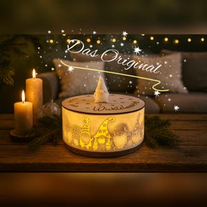 Könnte beinhalten: Ein runder Kerzenhalter aus Holz mit einem geschnitzten Zwergen-Design. Der Kerzenhalter ist von innen beleuchtet und strahlt ein warmes Licht aus. Eine kleine Zwergenfigur sitzt oben drauf. Der Text "Das Original" ist sichtbar.