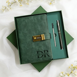 May include: A green leather journal with a combination lock, presented in a matching gift box. The journal has the initials "DR" and the name "DYLAN REEVES" printed on the cover. A pen and a stylus are included.