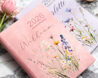 May include: Two 2026 schedule notebooks. One is pink with the name "William" and floral illustrations. The other is lavender with the name "Charlotte" and floral illustrations. Both have the year 2026 printed on the cover.