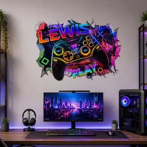 Puede incluir: Un adhesivo de pared que muestra un mando de videojuegos negro con detalles en amarillo neón y naranja, rodeado por un efecto de pared agrietada. El texto "LEWIS" aparece en letras naranjas sobre el mando y "PLAY" en azul debajo.