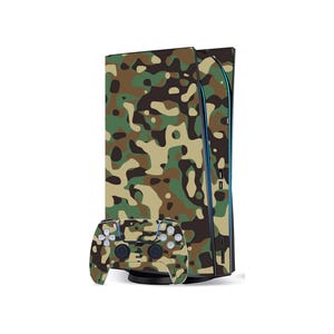May include: A camouflage-patterned gaming console and controller. The console is upright, with a vertical design, and the controller is positioned in front. The camouflage design features shades of green, brown, and tan.