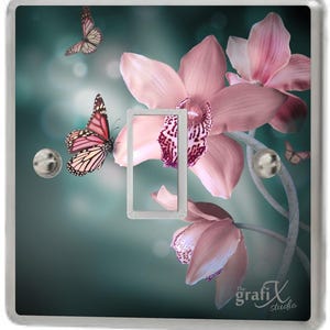 Peut inclure: Une plaque de prise de courant avec un motif d'orchidées roses et de papillons sur un fond bleu-vert. Le texte "The grafix studio" est dans le coin inférieur droit.