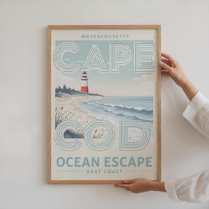 May include: A vintage-style poster with a blue and white illustration of a lighthouse on a beach with waves. The text on the poster reads "MASSACHUSETTS CAPE COD OCEAN ESCAPE EAST COAST".