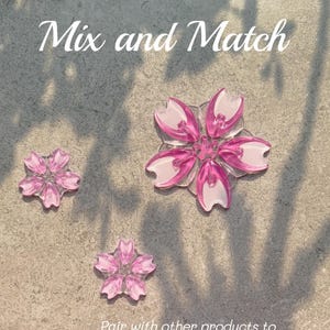 May include: Three pink and white flower-shaped decorations on a textured surface. The text "Mix and Match" is at the top, with additional text below. The decorations are for a personalized snowboard design.