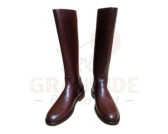 May include: A pair of tall, dark brown leather riding boots. The boots are knee-high with a smooth, polished finish. The soles are a darker shade of brown. The boots are designed for equestrian activities.