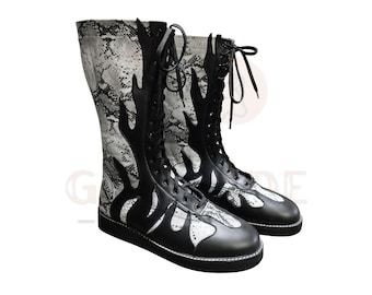 Puede incluir: Un par de botas altas en blanco y negro. Las botas presentan un estampado de piel de serpiente en la caña superior y un diseño de llama en cuero negro. Tienen cordones y suelas negras.