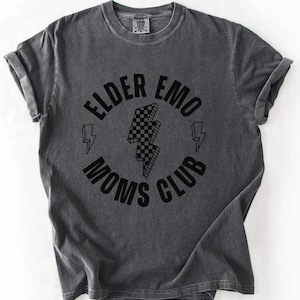 Op de afbeelding: Een donkergrijs T-shirt met een zwarte grafische print van een geruite bliksem in een cirkel met de tekst "Elder Emo Moms Club".