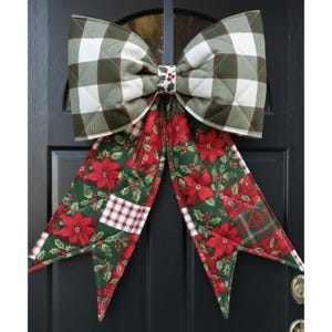 May include: A large quilted fabric bow featuring a green and white buffalo check pattern on the top loops and a festive red poinsettia and holly leaf print on the long hanging tails, with a small center band decorated with holly berries.
