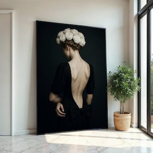 May include: A woman in a black dress with a low back and a white flower crown. The background is a dark, solid color.