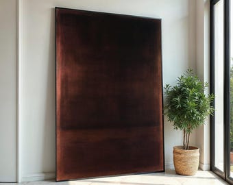 May include: A large abstract painting in a black frame hangs on a white wall. The painting is a dark brown color with subtle variations in shade. The painting is in a modern style and would be a great addition to any home.