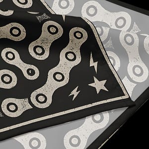 May include: Black bandana with a repeating bicycle chain pattern in off-white. The design includes a star and lightning bolt accents. The bandana is folded, showing a corner of the design.