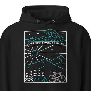 May include: Black hoodie with a white and teal graphic. The graphic features a sun, mountains, trees, a tent, and a bicycle. The text "JOURNEY BEYOND LIMITS" is above the sun and mountains.