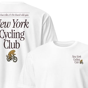 Könnte beinhalten: Zwei weiße T-Shirts mit dem Text "New York Cycling Club" in brauner Schrift. Eines hat einen kleinen Radfahrer auf der Vorderseite, das andere den Clubnamen und einen Radfahrer auf Vorder- und Rückseite. Auf der Rückseite steht auch "More than miles, it's the shared wild spirit."