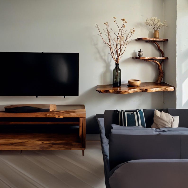 May include: A dark wood TV stand with two shelves and a dark wood floating shelf with a vase of dried branches and a bowl. A dark gray couch with pillows is in the background.
