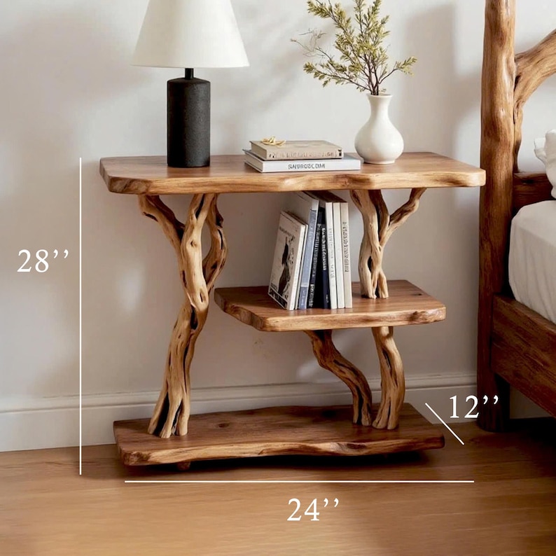 May include: A rustic wooden side table with a natural tree branch design. The table has two shelves and measures 28 inches high, 24 inches wide, and 12 inches deep. A lamp, books, and a vase with greenery are displayed on the table.