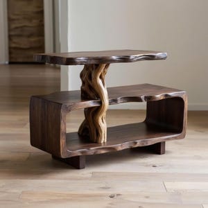 Puede incluir: Una mesa auxiliar de madera de dos niveles con un tronco de árbol natural que sostiene el estante superior. La mesa tiene un acabado marrón oscuro con un diseño de borde vivo y mide aproximadamente 76 cm de largo, 46 cm de ancho y 51 cm de alto.