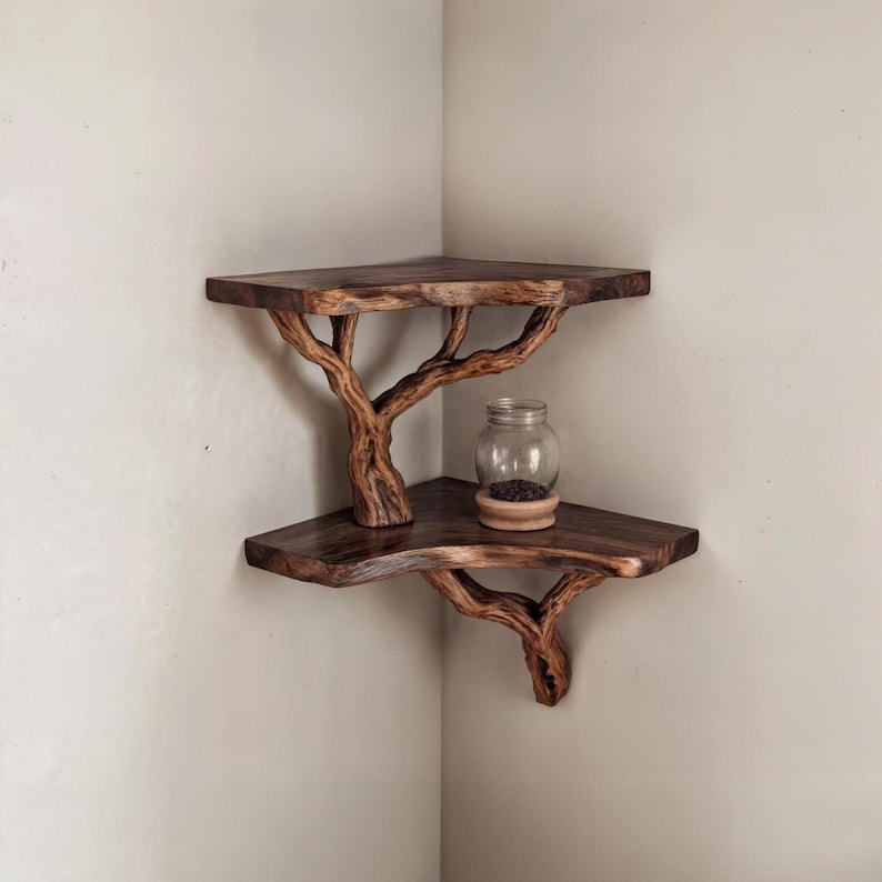 May include: A two-tiered corner shelf made from natural wood branches. The shelf is stained a dark brown color and has a rustic, organic look. A small glass jar with black contents sits on the top shelf.