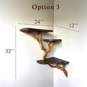 Może przedstawiać: Regal narożny z trzema p&oacute;łkami wykonanymi z ciemnego drewna i naturalnych gałęzi. P&oacute;łki mają 61 cm szerokości, 30 cm głębokości i 81 cm wysokości.