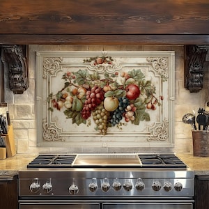 May include: A decorative kitchen backsplash featuring a still life of various fruits, including grapes, apples, and pears. The artwork is framed with ornate detailing and set against a neutral background. The kitchen also features a stainless steel stove.