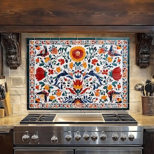 May include: A decorative kitchen backsplash with a vibrant floral design. The artwork features a white background with red, orange, yellow, and blue flowers and leaves. The backsplash is framed with a green border and is installed above a stainless steel gas range.