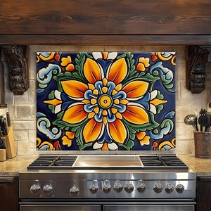 May include: A decorative kitchen backsplash featuring a large, stylized floral design. The flower has orange and yellow petals, green leaves, and a blue center, set against a dark blue background. The backsplash is installed above a stainless steel gas range.