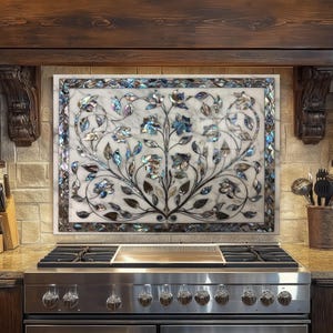 May include: A rectangular marble backsplash with a floral design above a stainless steel stove. The design features blue, silver, and brown floral patterns set against a white marble background. The backsplash is framed with a decorative border.